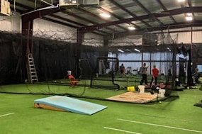 Indoor entertainment facility with turf, batting cages, and people practicing